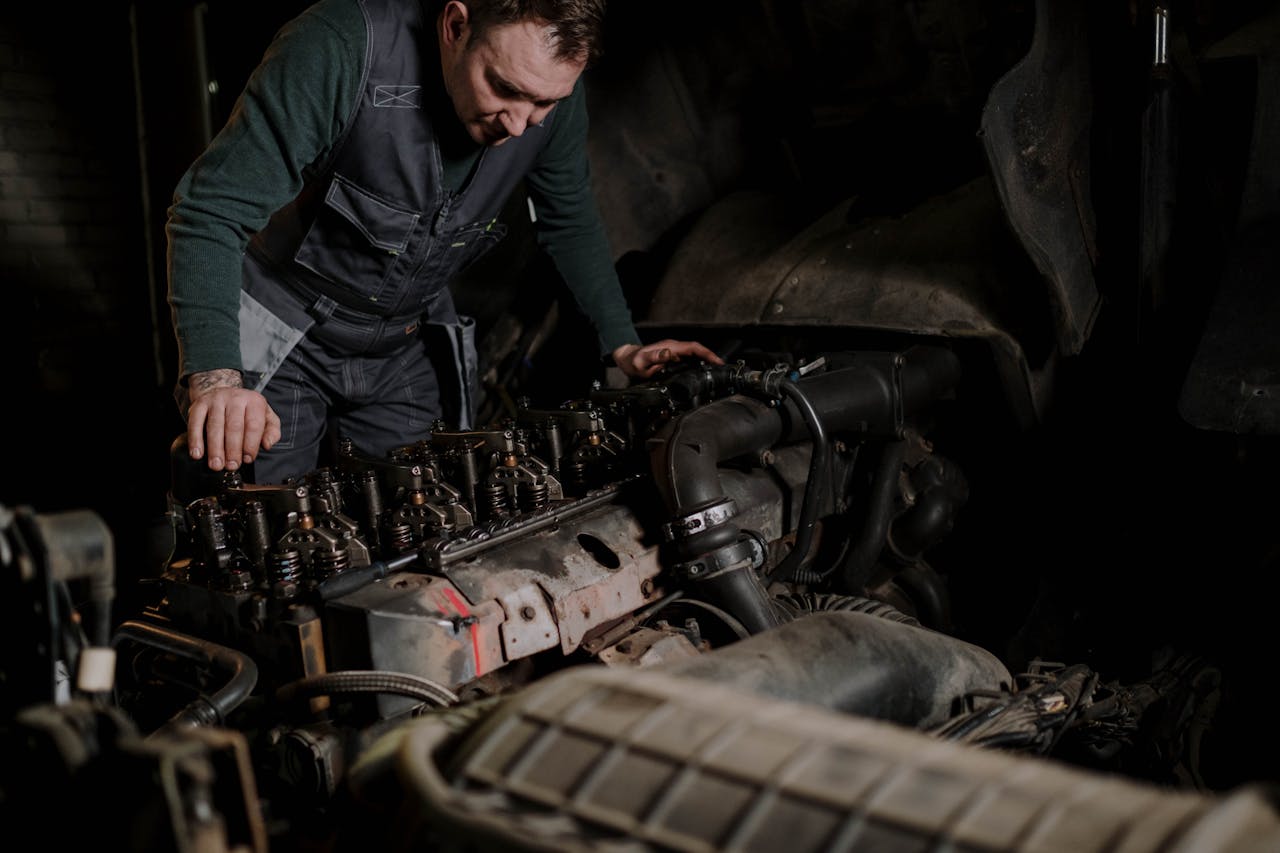 Mechanic focused on vehicle engine repair in an indoor workshop.
